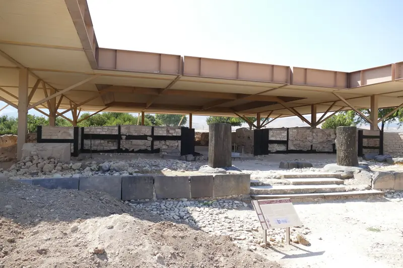 שרידי הארמון הכנעני בתל חצור תחת גג הגנה גדול, עם מדרגות ושני עמודי בזלת