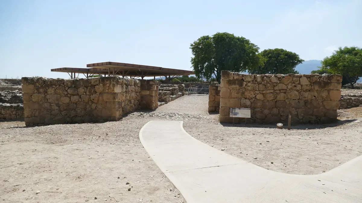 שני גושי קירות אבן משני צדי שביל, וברקע גג הגנה