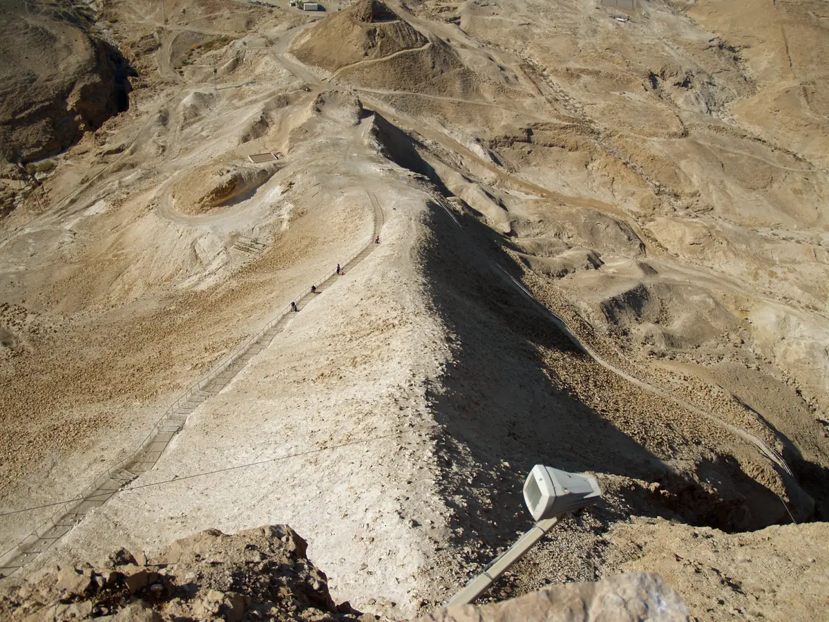 סוללת עפר בהירה וארוכה העולה ממישור המדבר אל פסגת מצדה, במבט מלמעלה