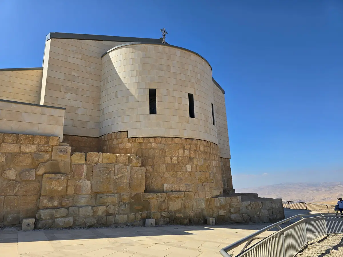 Abside arrondie en pierre claire du Mémorial de Moïse, posée sur des murs antiques, sous un ciel bleu