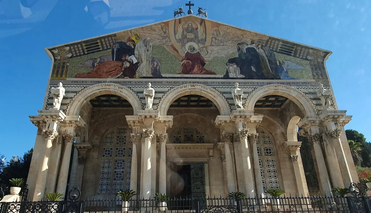 Façade of the Church of All Nations: three-arched portico with columns, statues on top and a large golden mosaic on the pediment