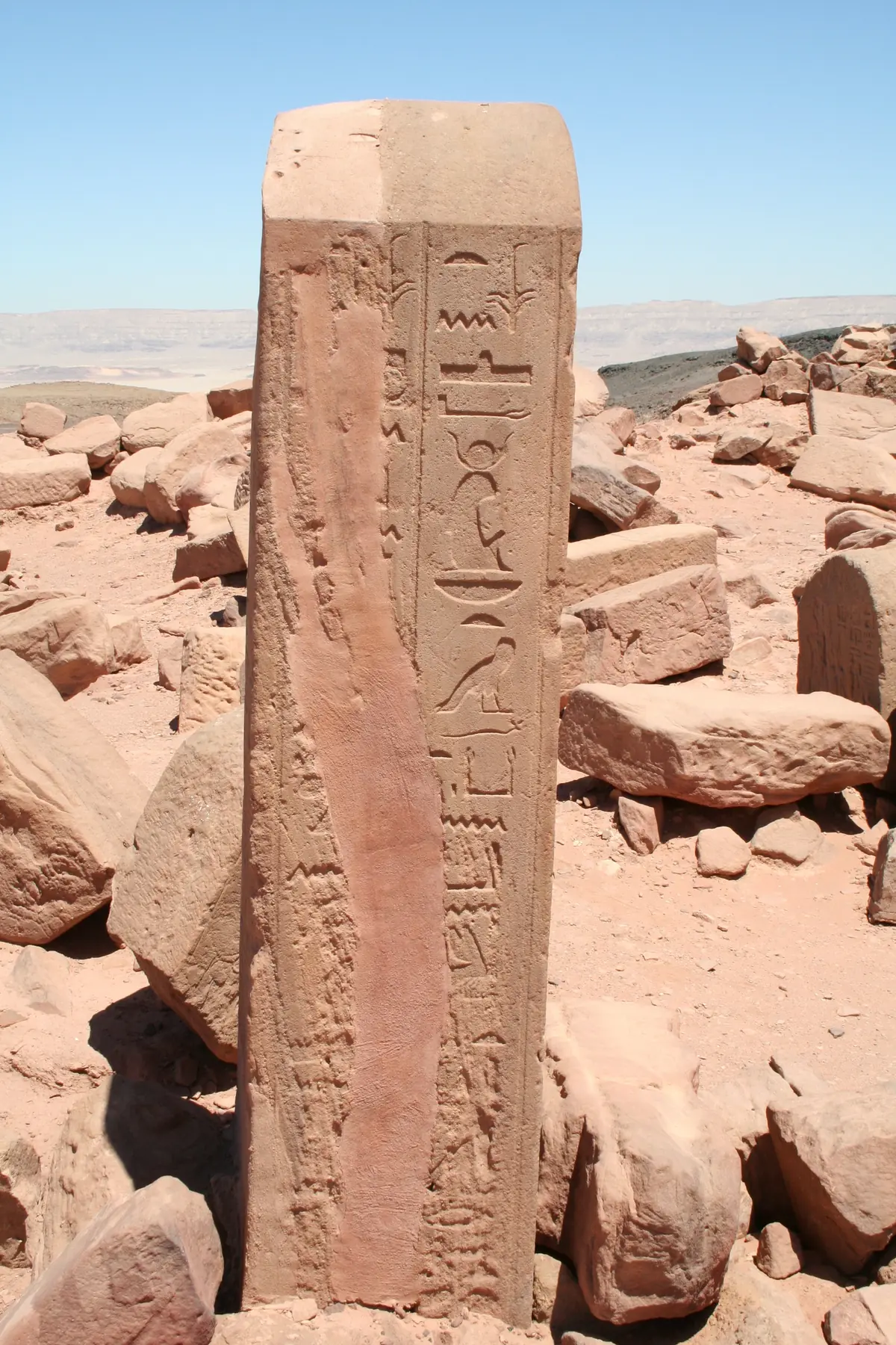 Haute stèle de grès couverte de hiéroglyphes, dressée devant l'horizon du désert