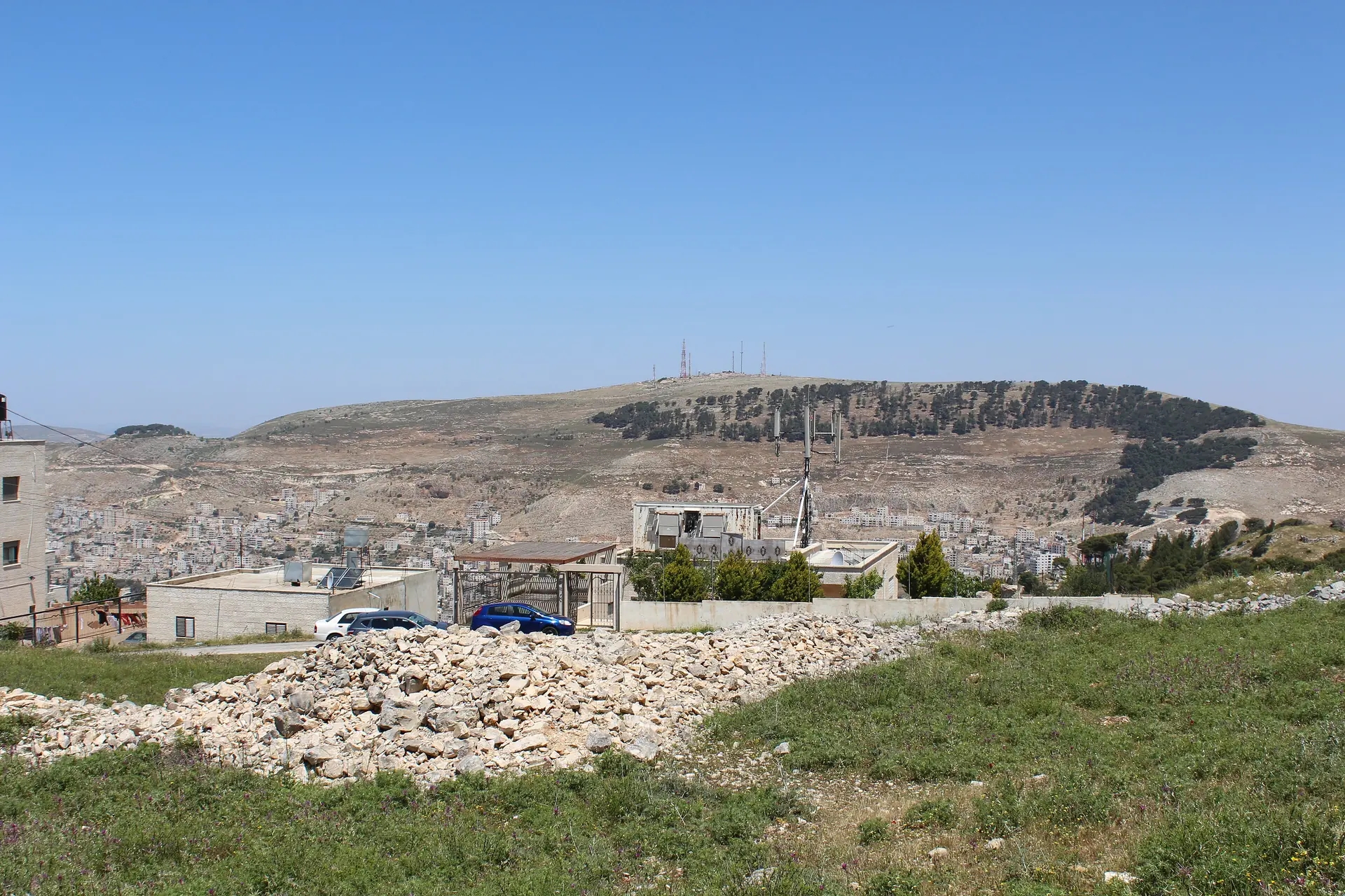Mount Ebal, a bare hill topped with antennas and edged with pines, above the houses of Nablus